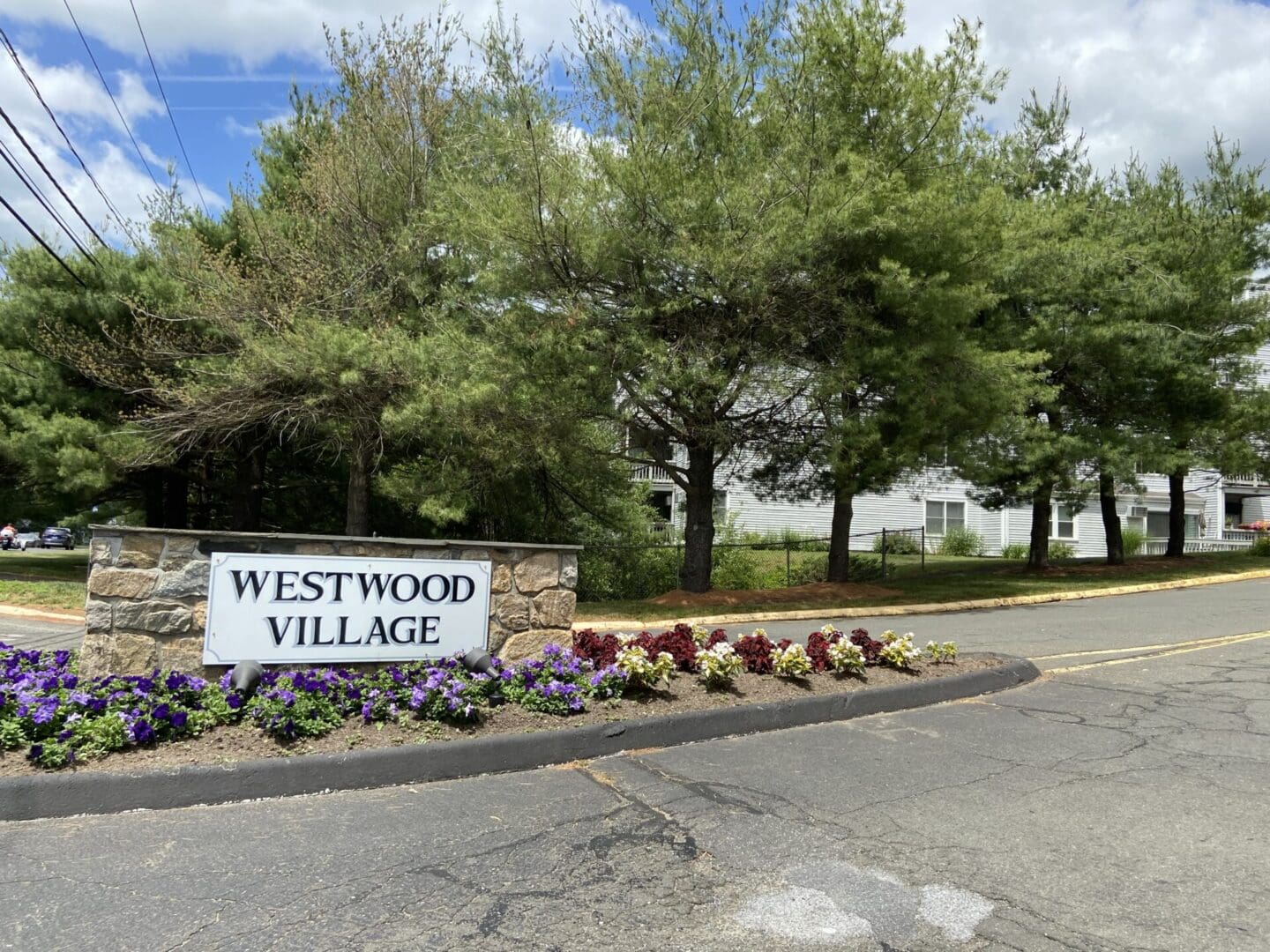 A sign that says westwood village in front of some trees.