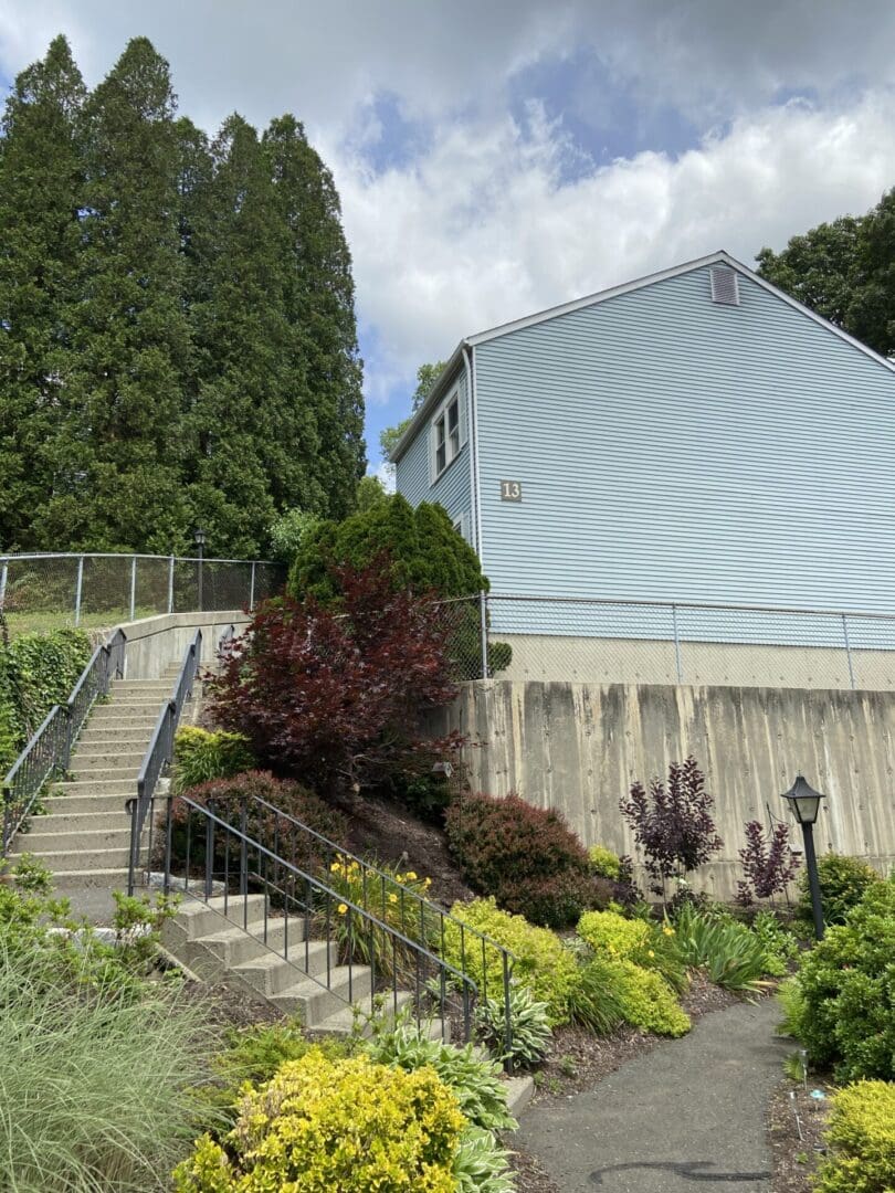 A house with stairs and bushes in front of it.