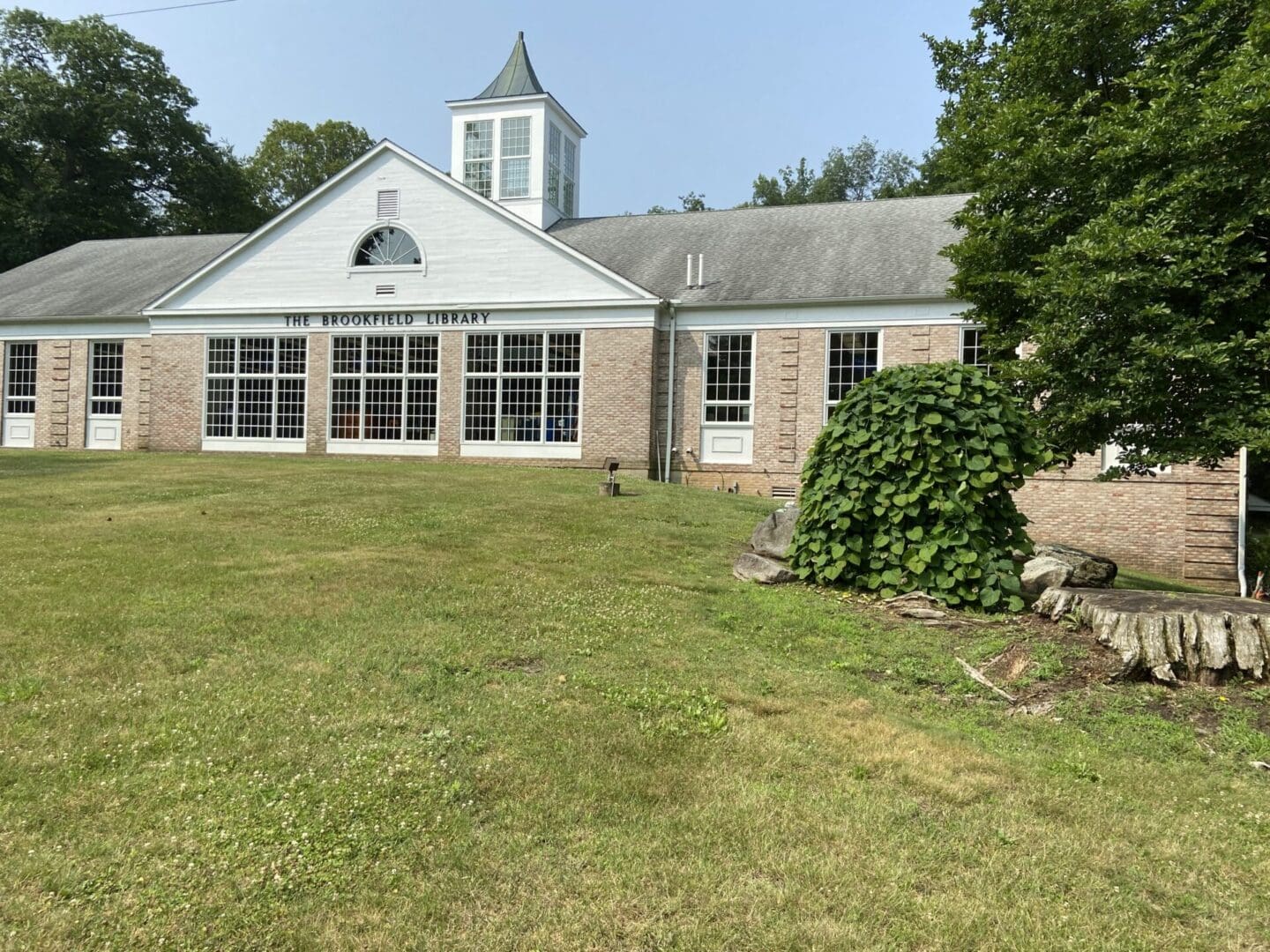 A large building with a steeple and a lawn.