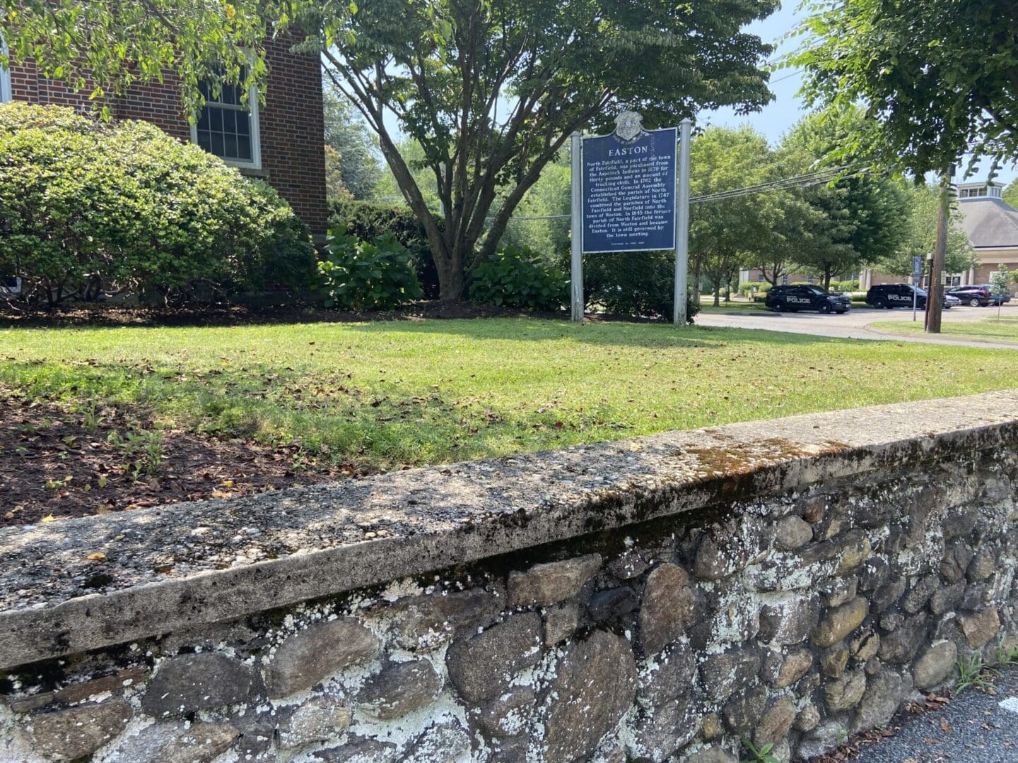 A sign on the side of a building near some grass.