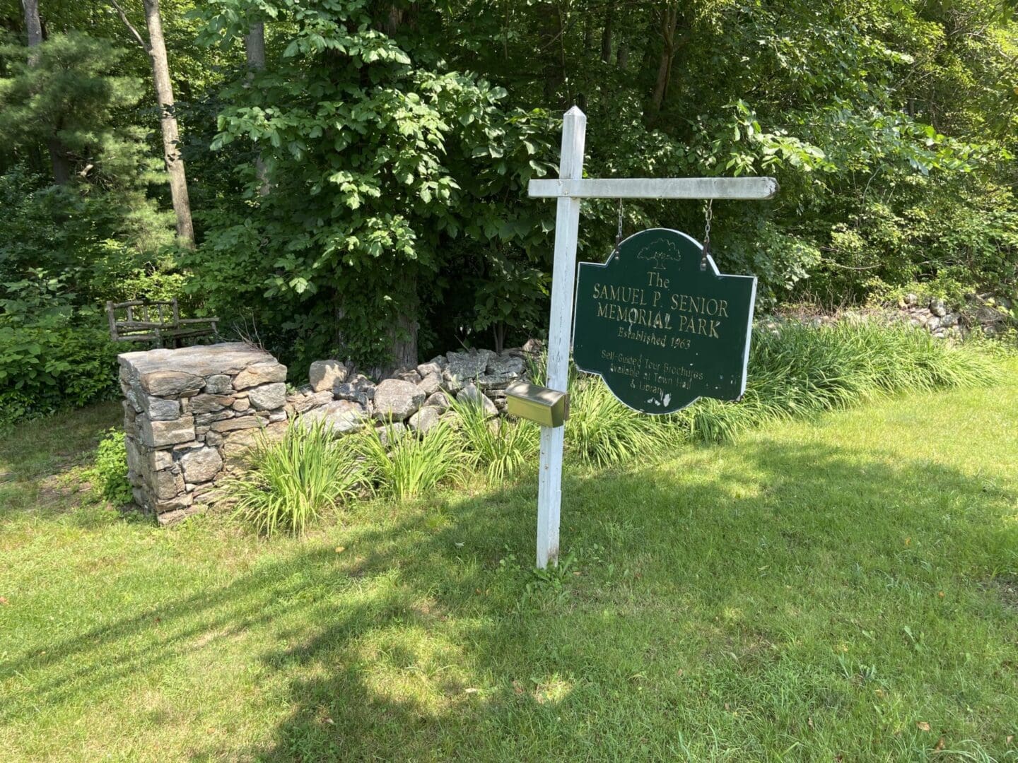 A sign in the grass near some trees