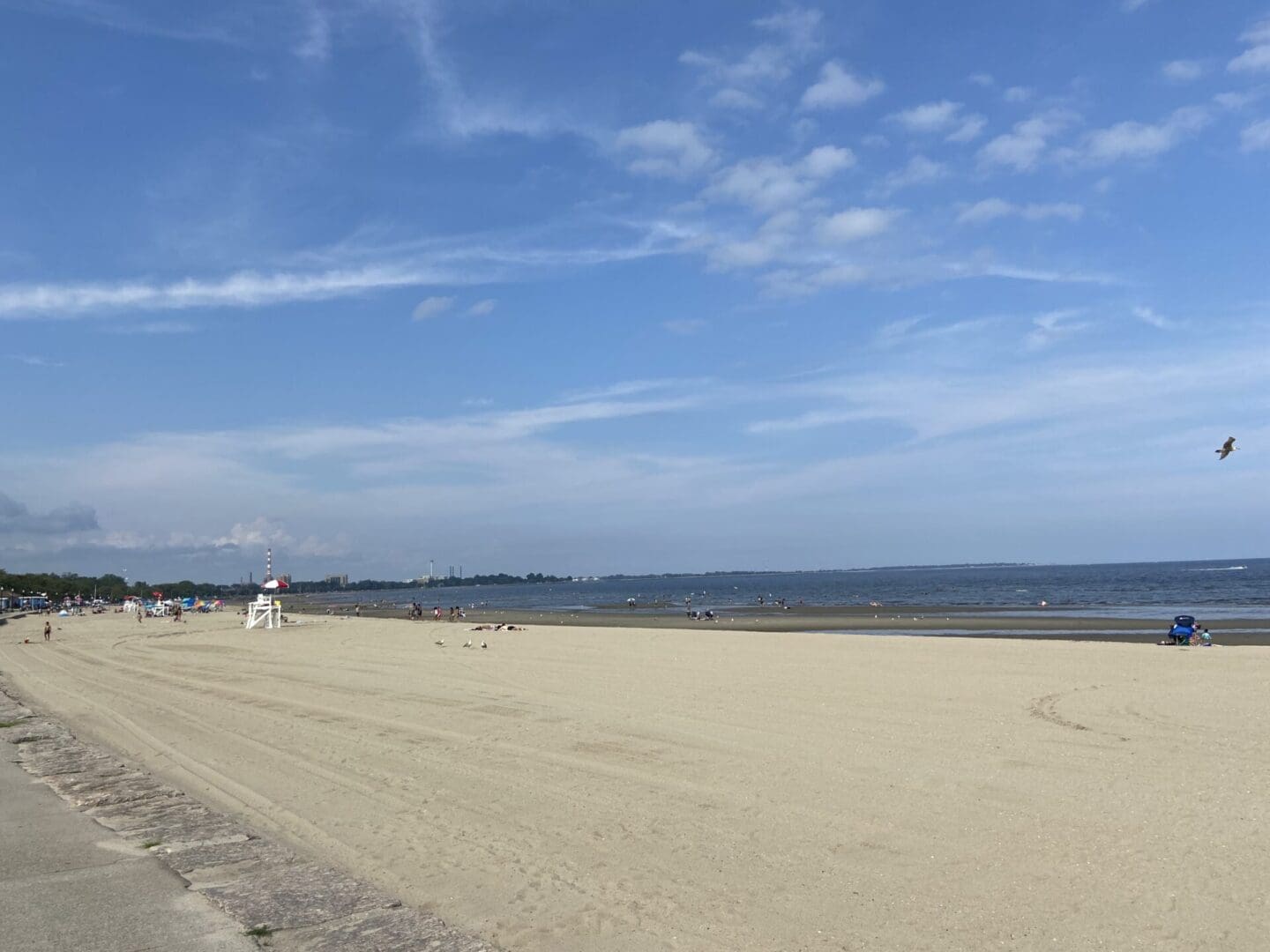 A beach with people walking on it and the ocean in the background.