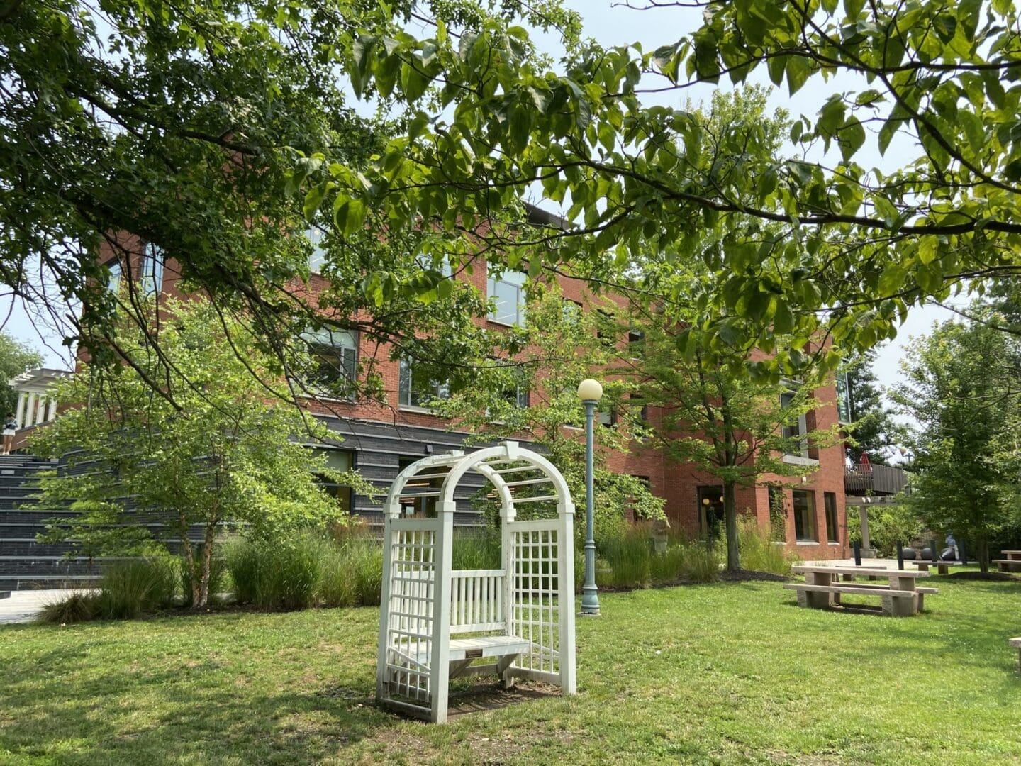 A white bench in front of a brick building.