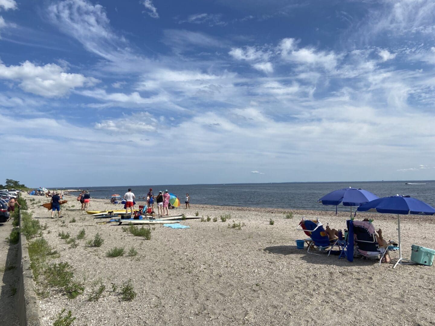 A group of people sitting on a sandy beach with umbrellas.