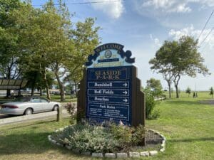 A sign in the grass with directions to several places.