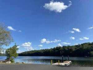 A lake with a dock and trees in the background.