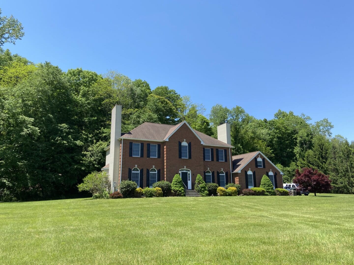 Brick house with green lawn and trees.