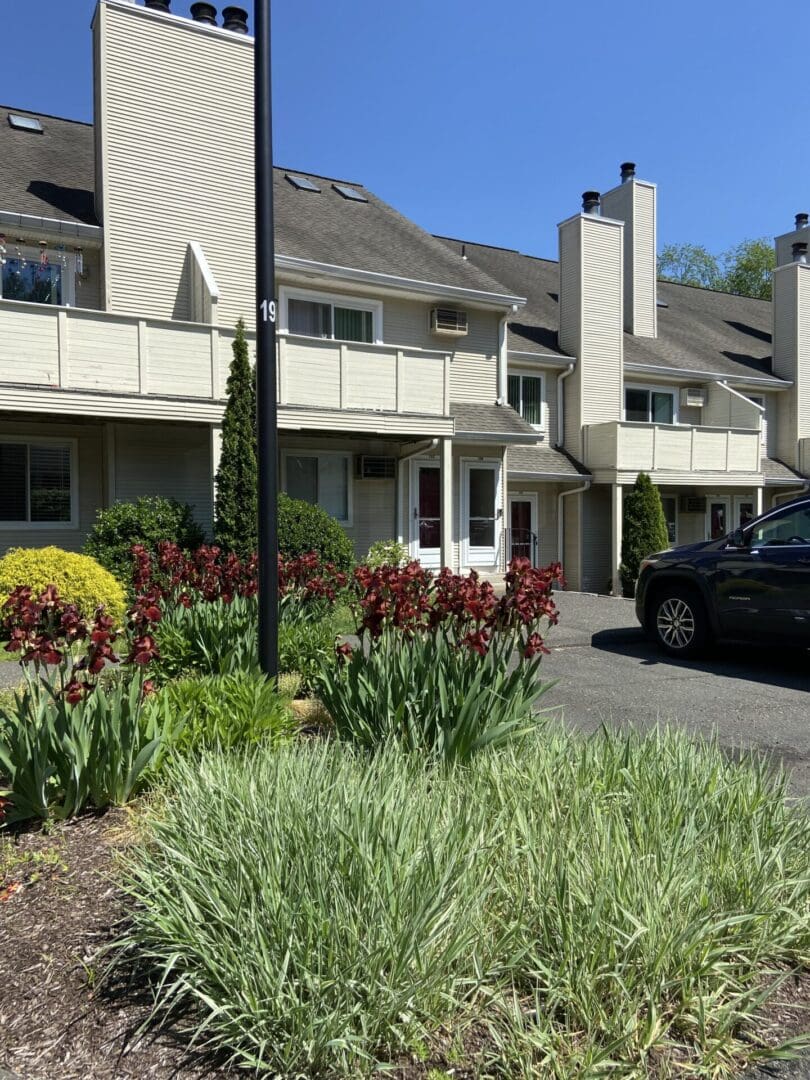 Apartment building with red flowers and a car.