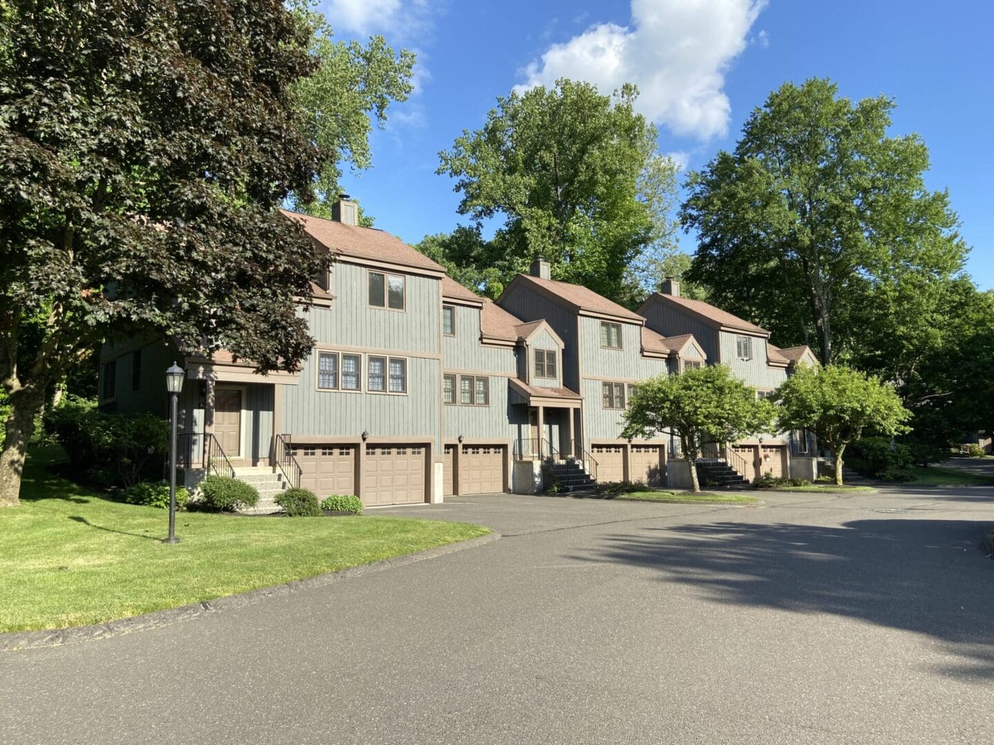 Gray townhouses with garages and landscaping.