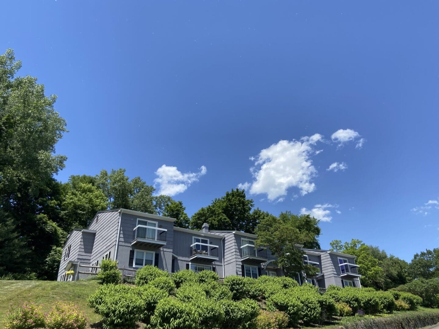 Gray townhouse with balconies under blue sky.