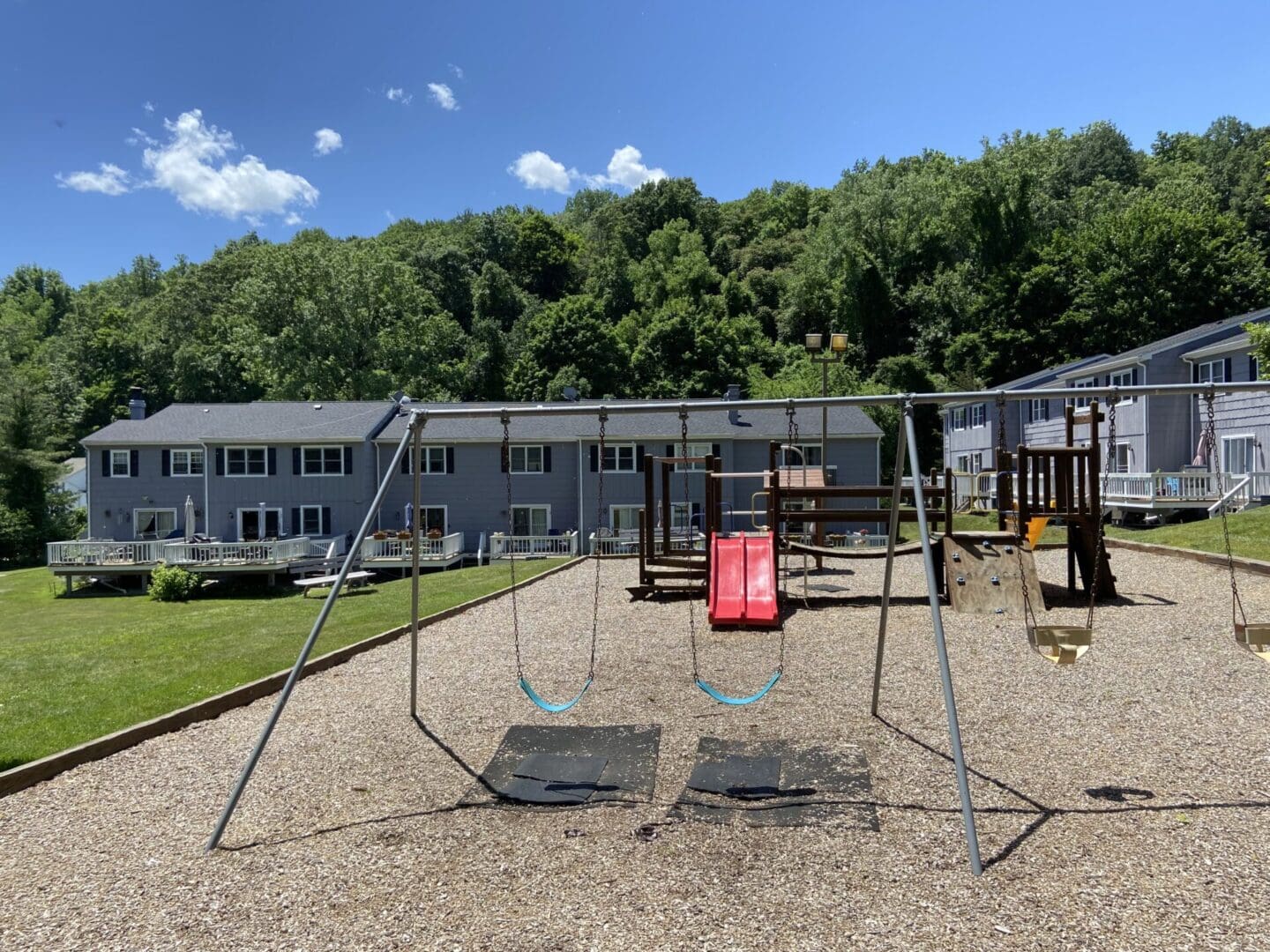 Playground with swings and a slide in front of houses.