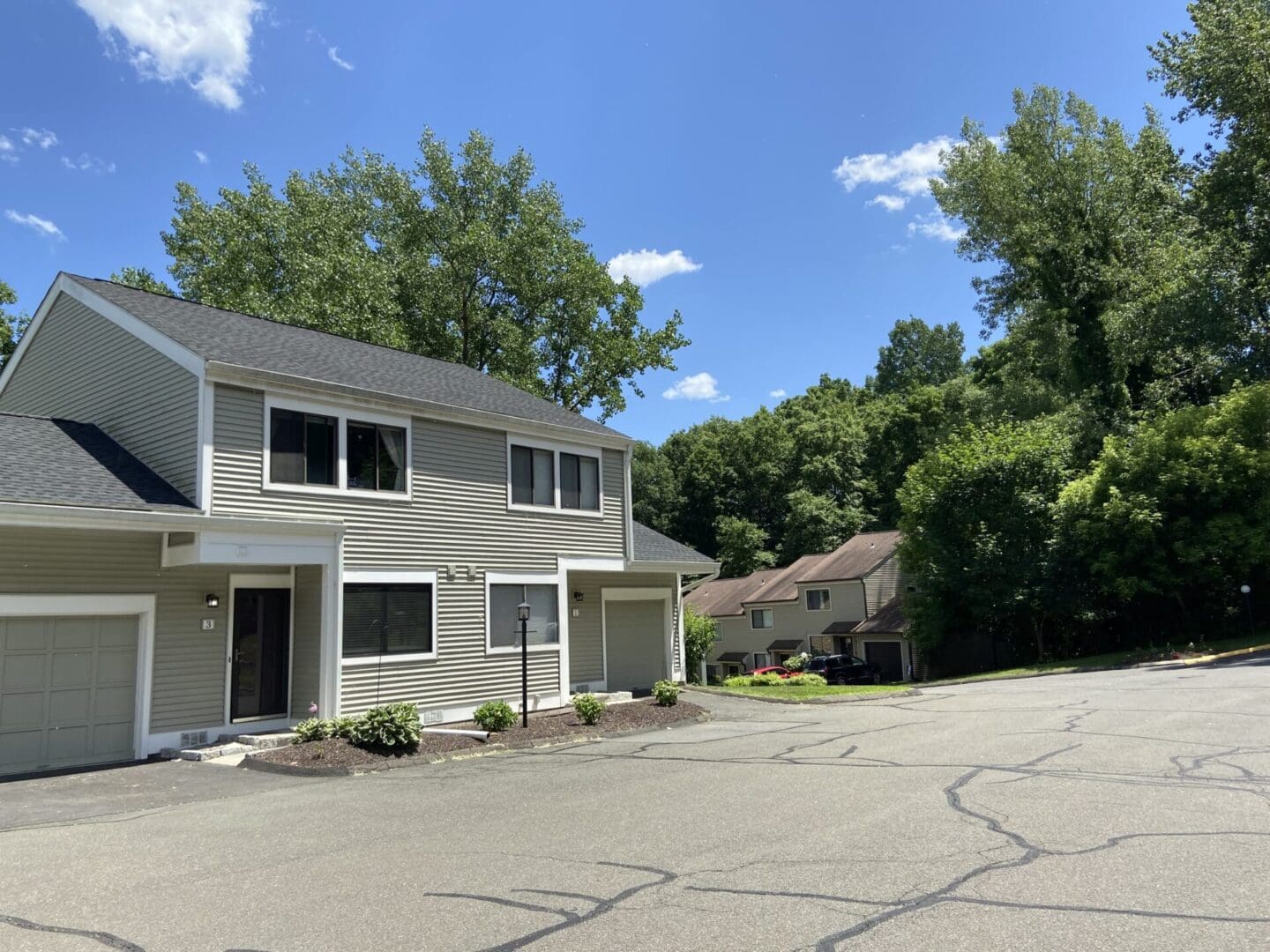 Two-story townhouse with garage and trees.