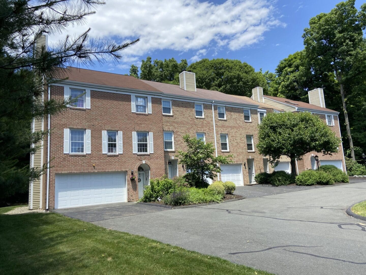 Brick townhomes with garages and a driveway.