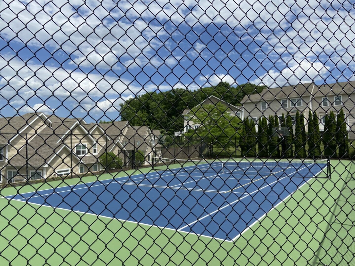 Tennis court viewed through a chain link fence.