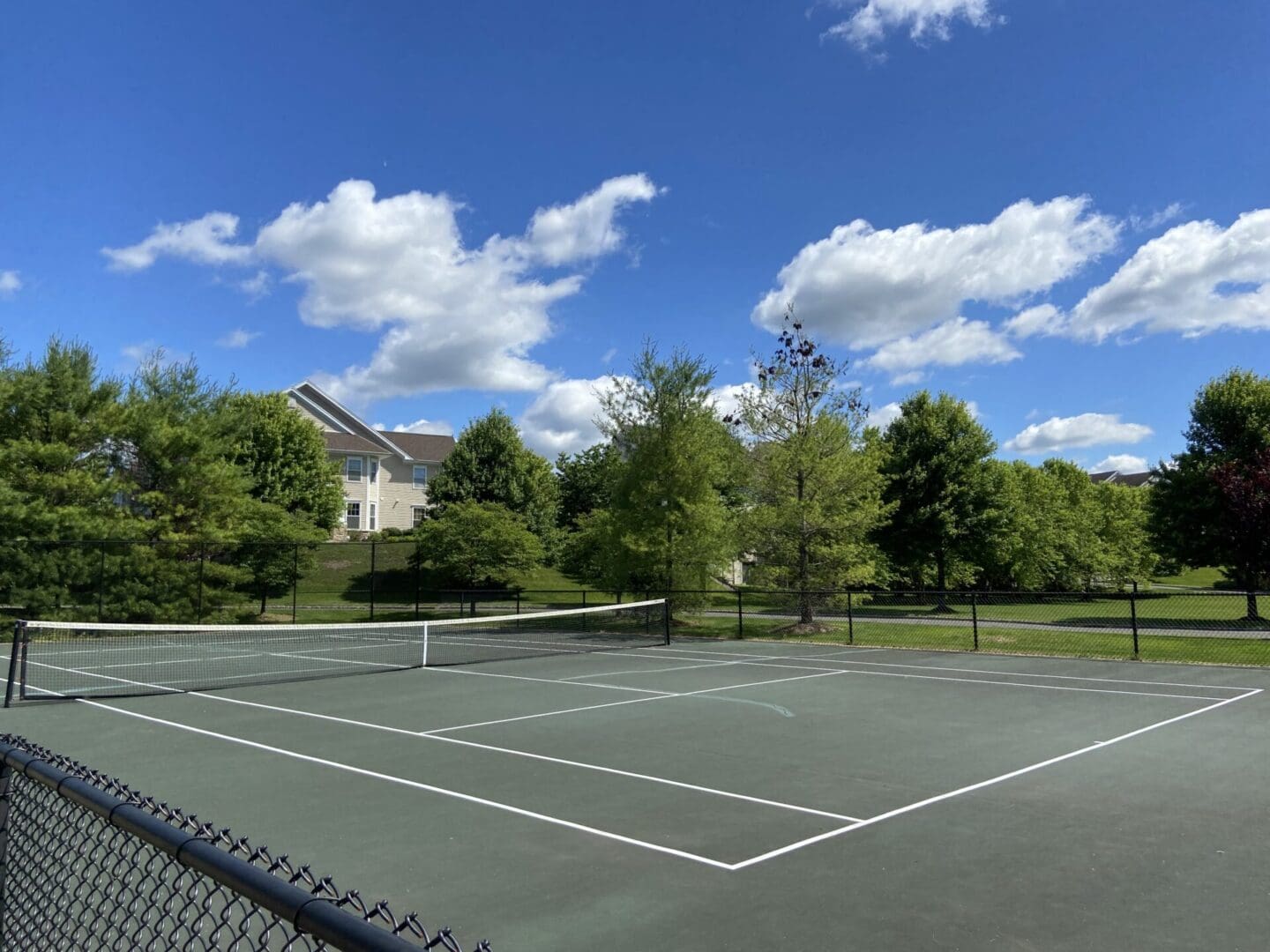 Outdoor tennis court under a blue sky.