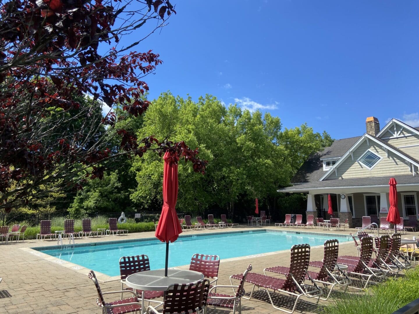 Outdoor pool with red umbrellas and chairs.