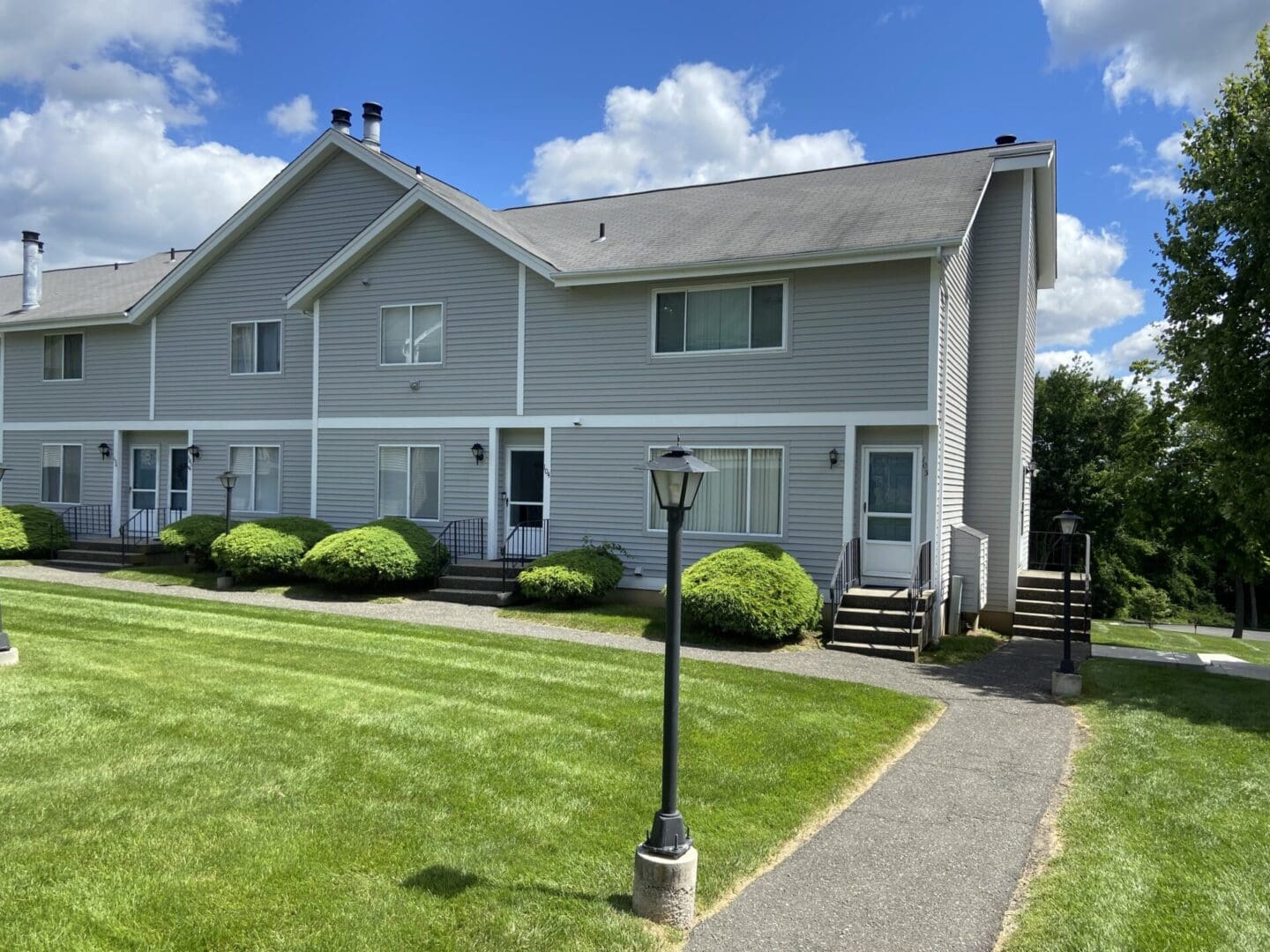 Gray townhouse with a front lawn.