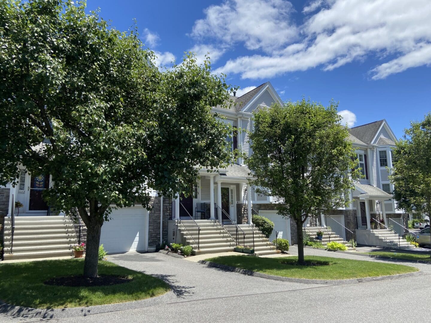 Townhouses with green lawns and trees.