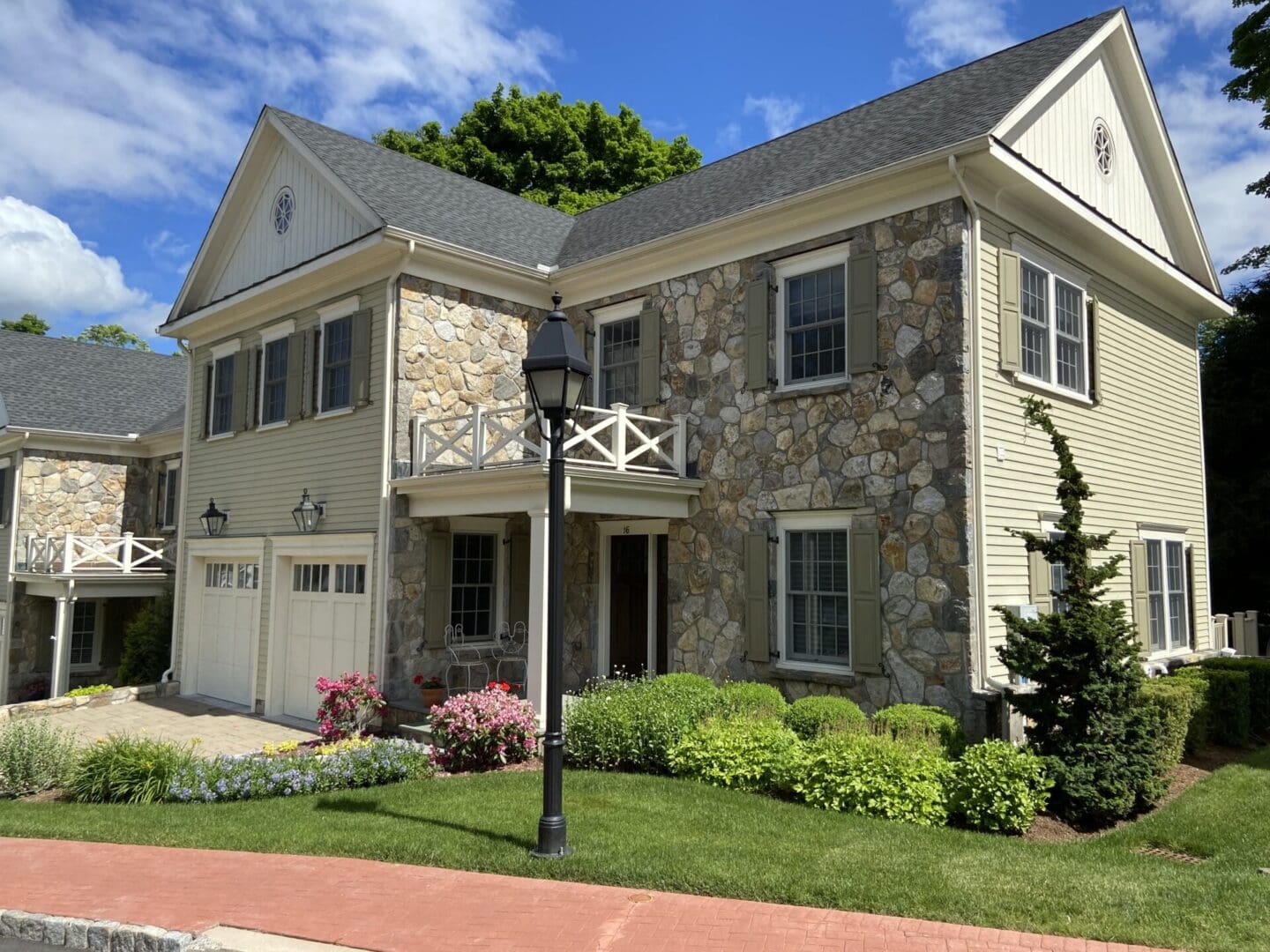 Stone house with double garage and landscaping.