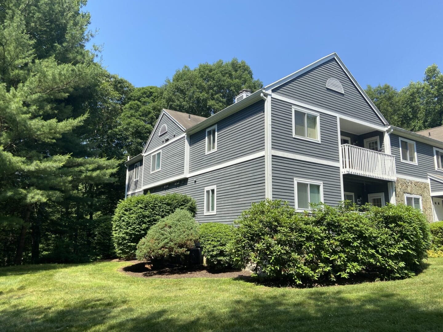 Gray house with white trim in woods.