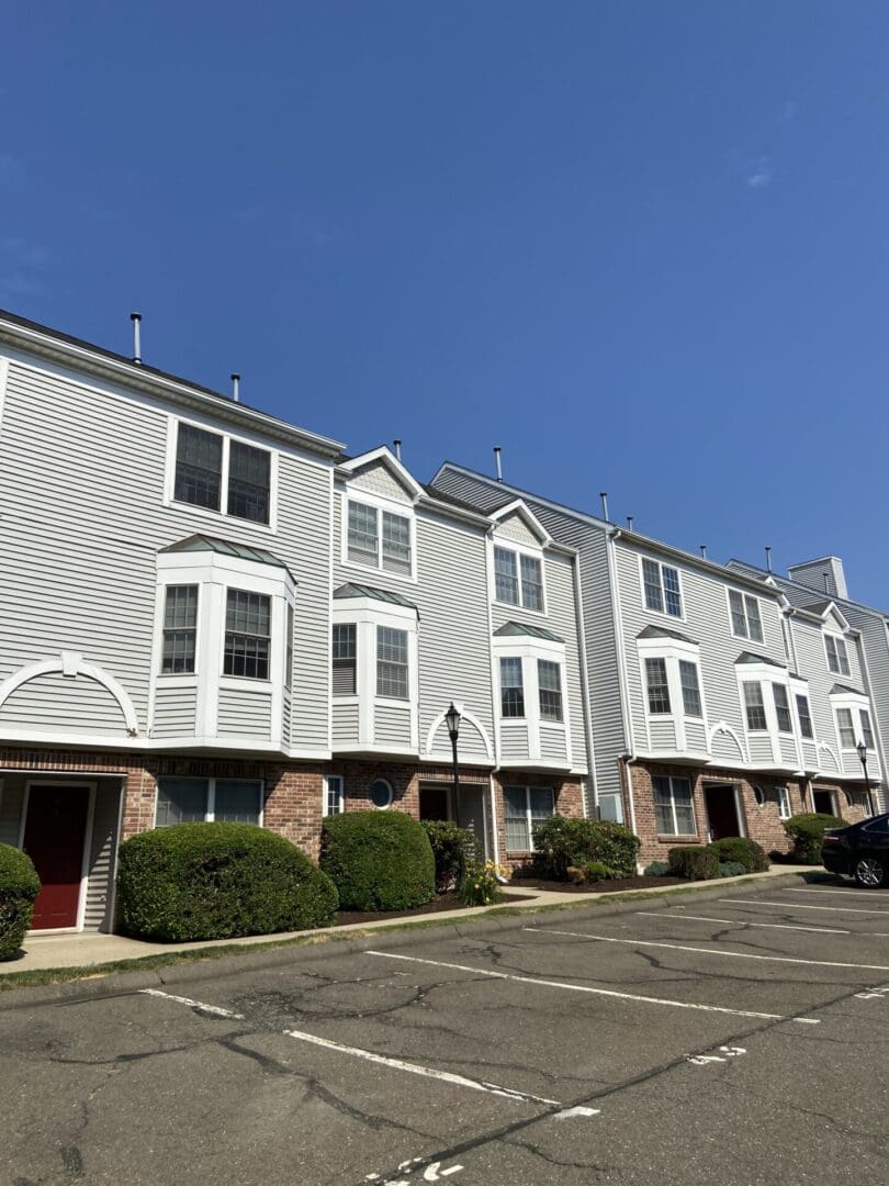 Gray townhouse with a paved parking lot.