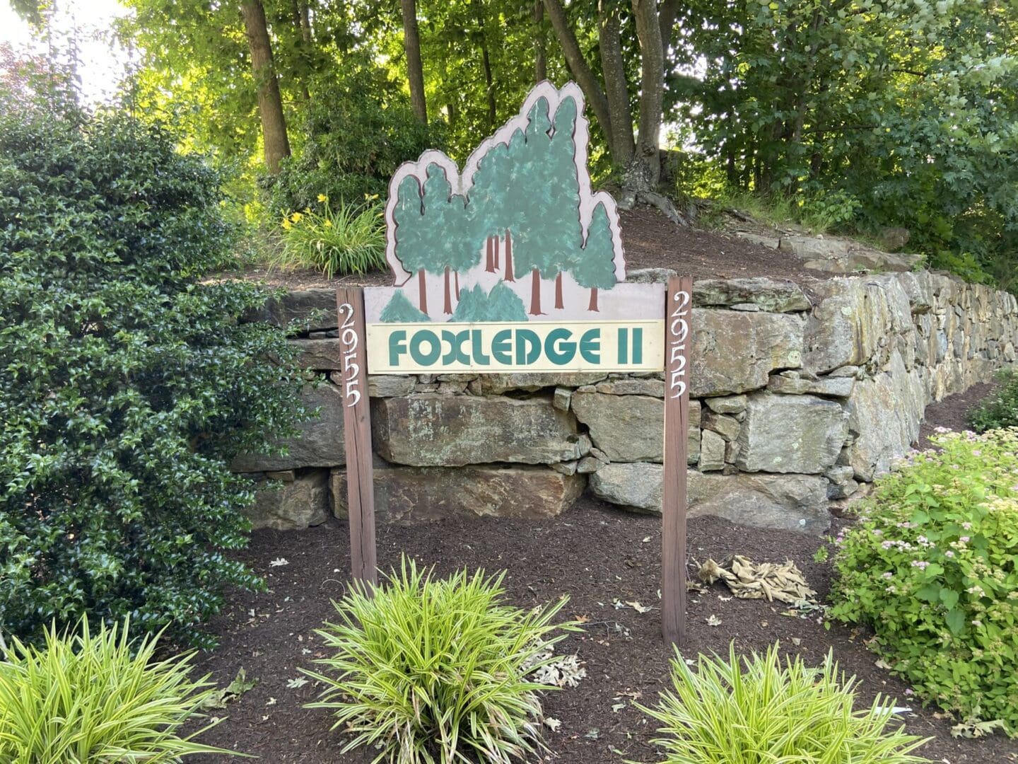 Foxledge II sign with trees and stone wall.