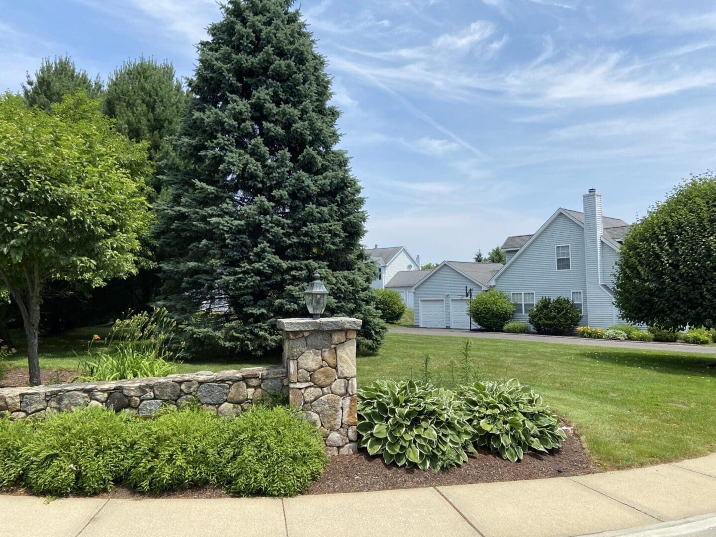 Stone wall and greenery in front of a house.