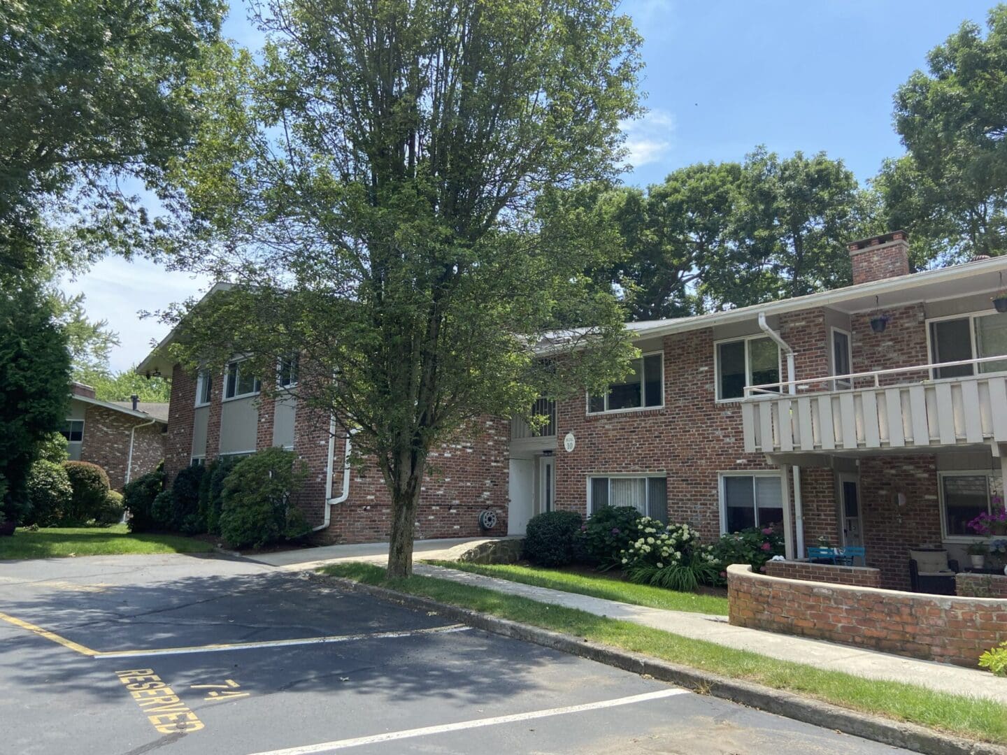 Brick apartment building with green trees.