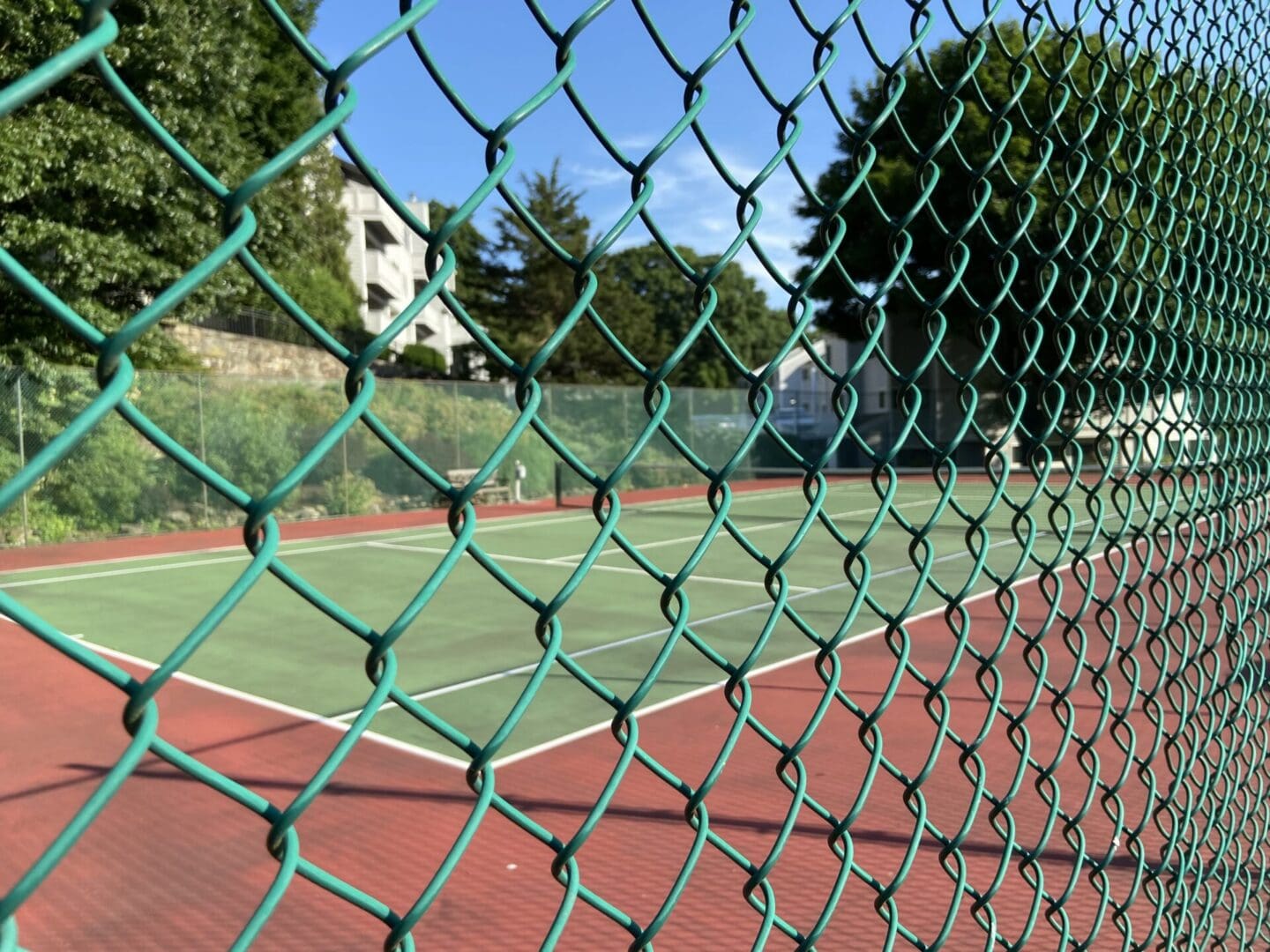 Green chain link fence over tennis court.