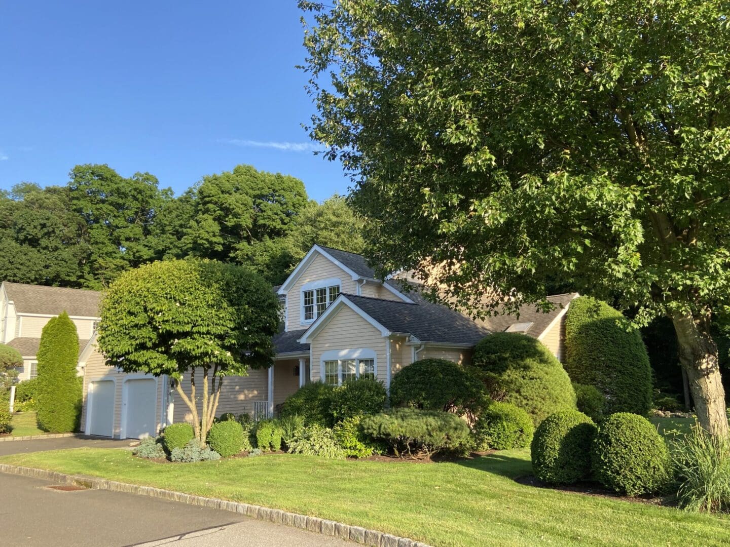 Yellow house with green lawn and trees.