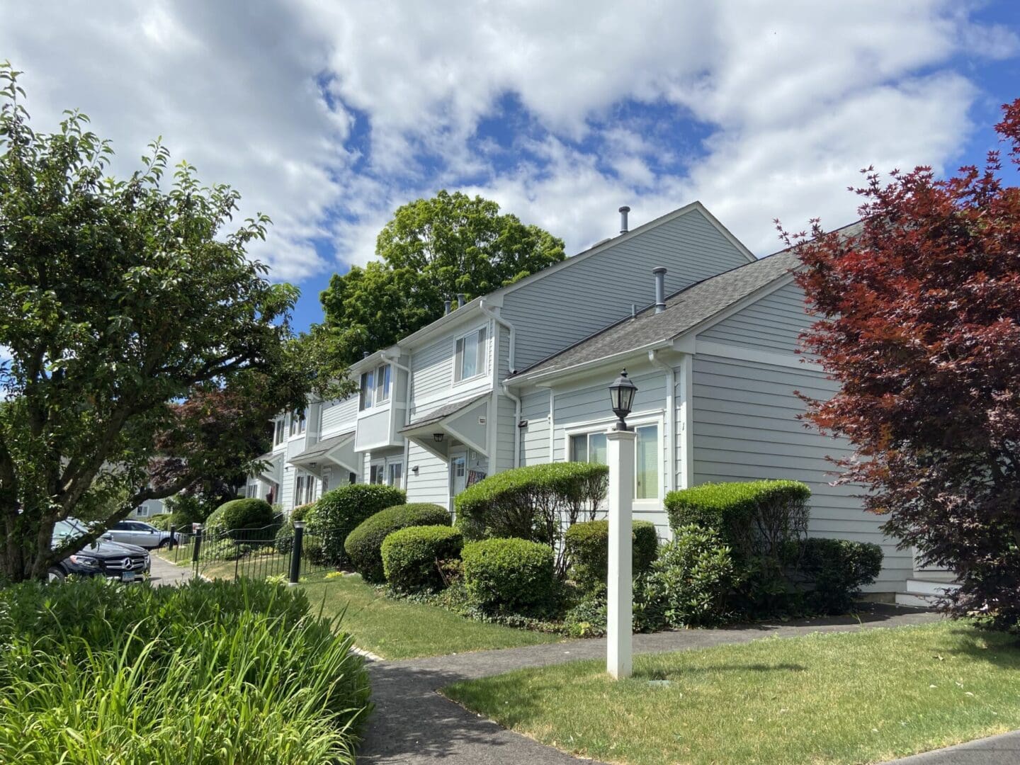 Gray townhouses, landscaped lawn, sunny day.