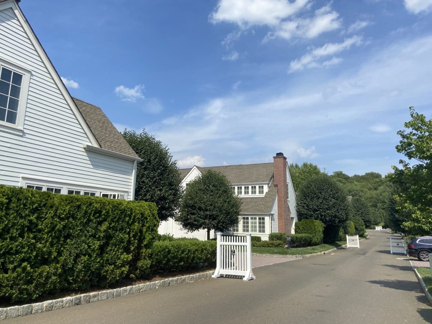 Suburban street with white houses and trees.