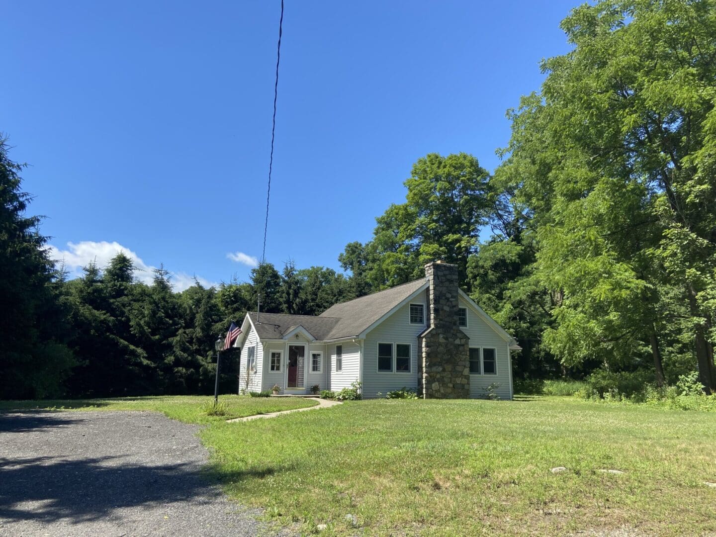 White house with stone chimney and flag.