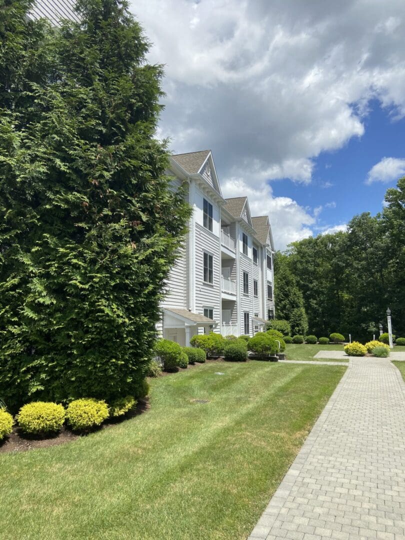 White apartment building with green lawn and walkway.