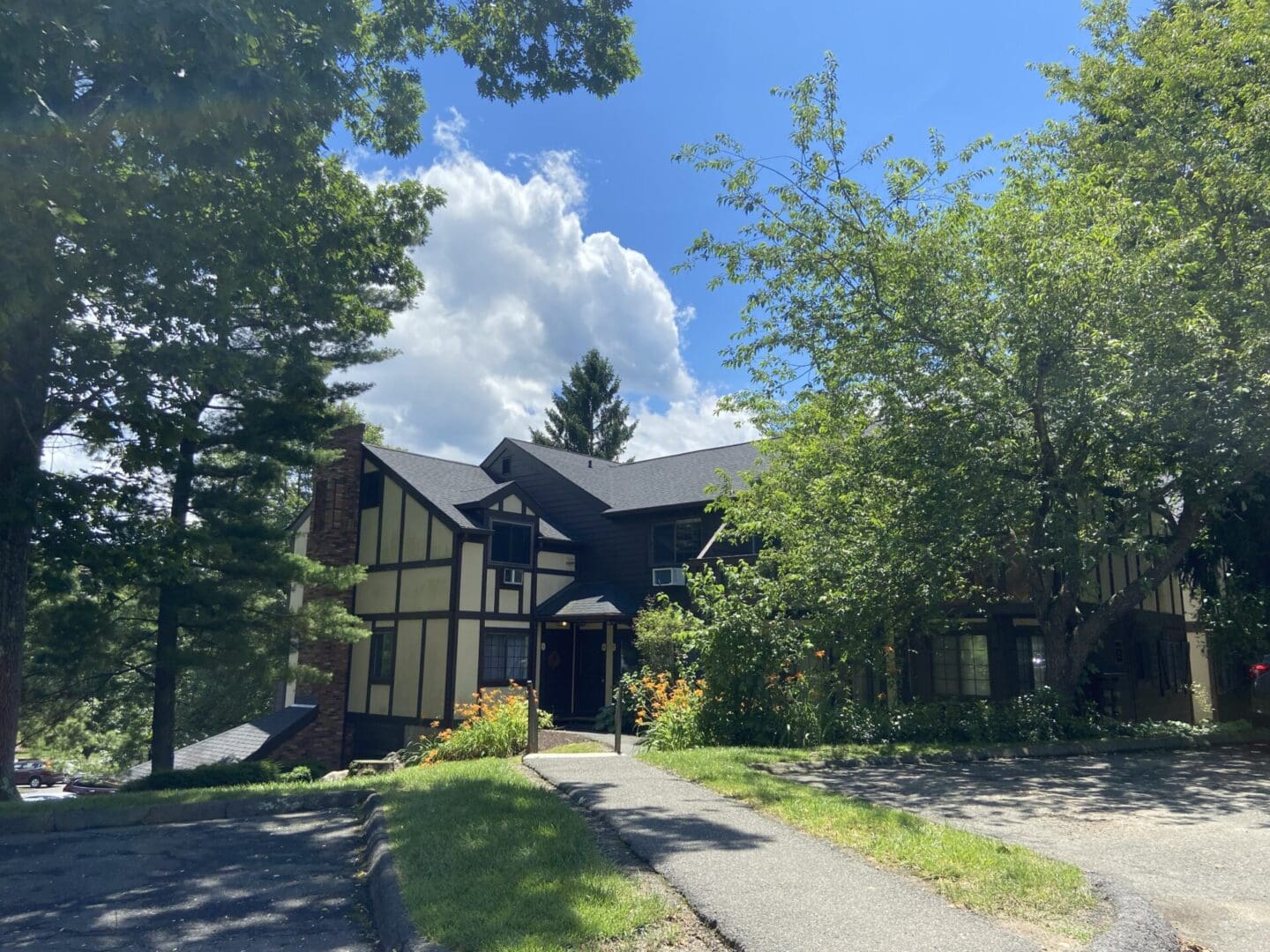 Two-story house with trees and walkway.