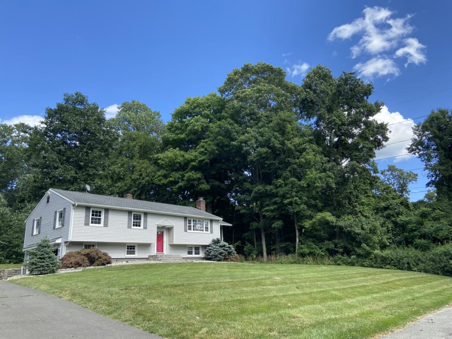 Gray suburban house with red door and lawn.