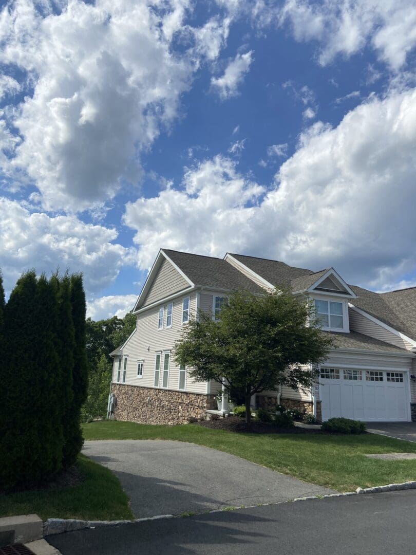 Two-story house with driveway and blue sky.