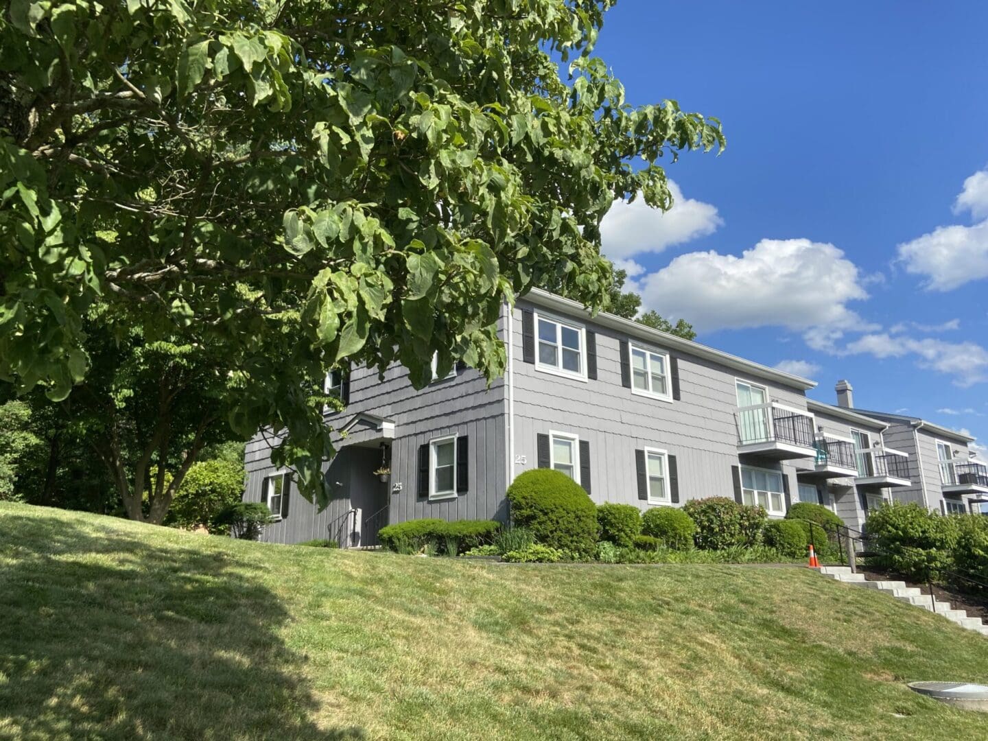 Gray apartment building with green lawn.