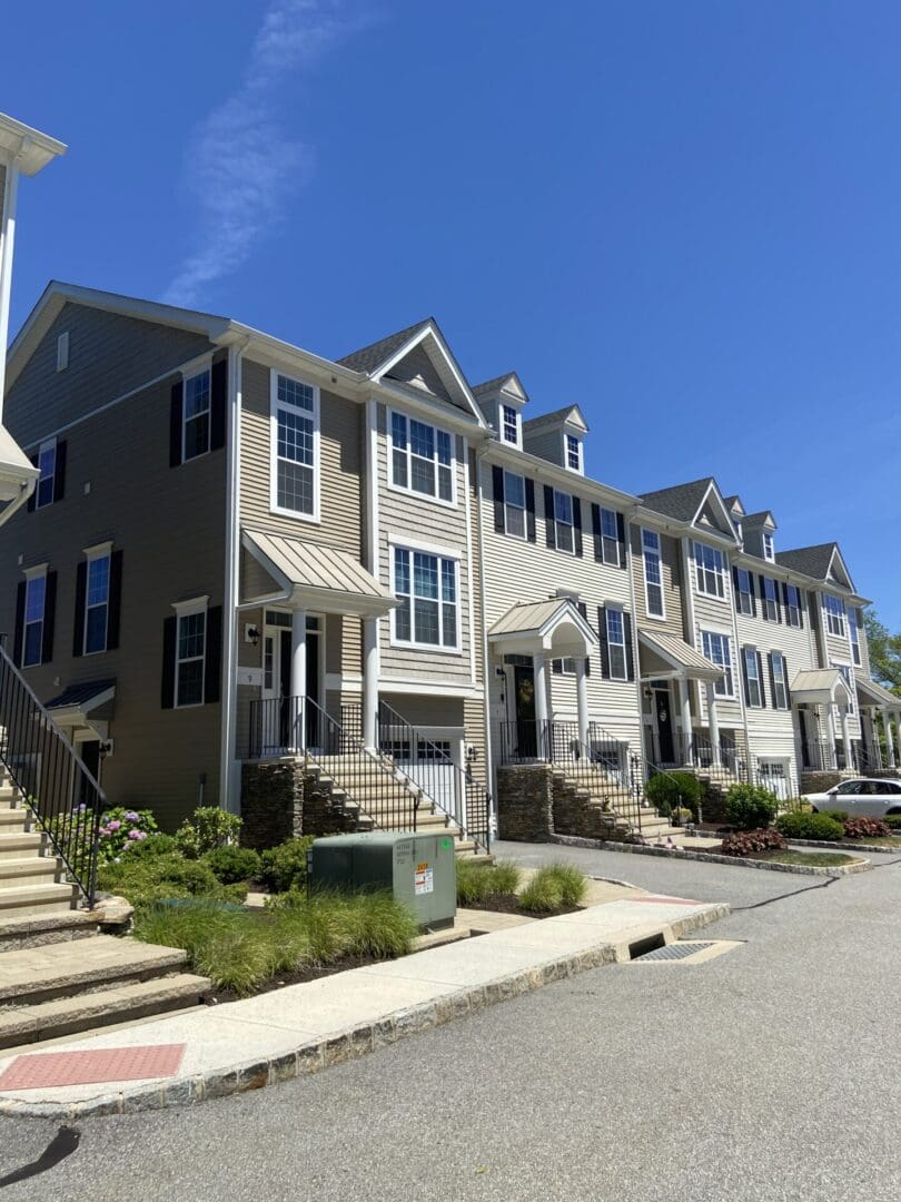 Tan townhouses with black windows and front steps.