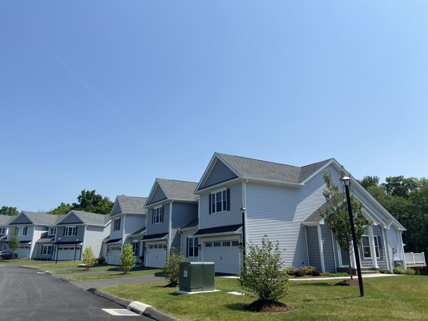 Row of gray houses with green lawns.