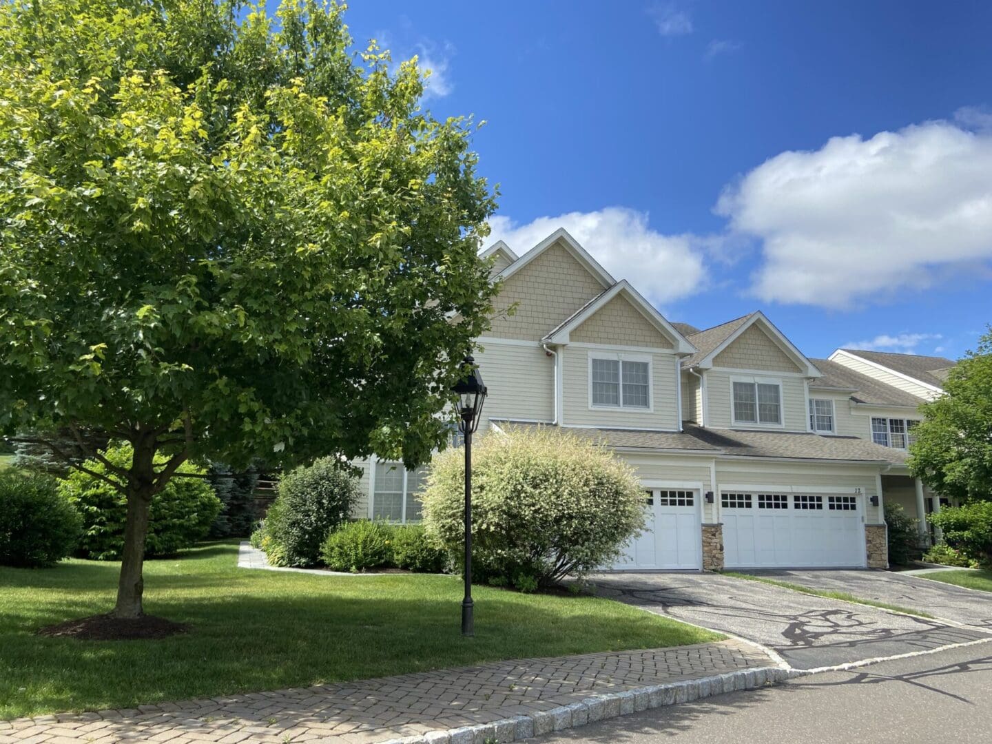 Tan townhouse with a front yard and driveway.