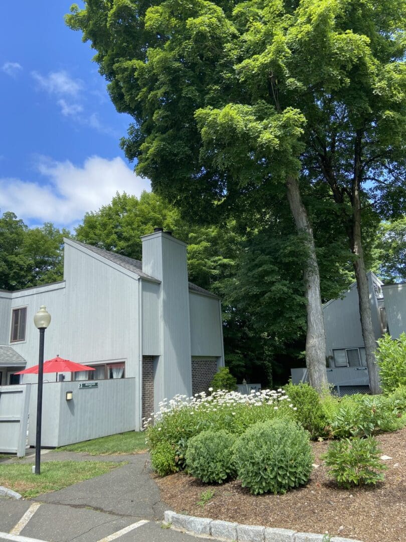 Gray house with green tree and flowers.