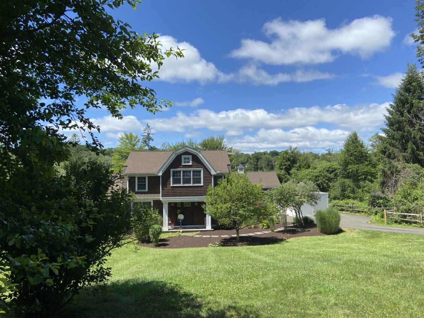 Brown house with green lawn and trees.