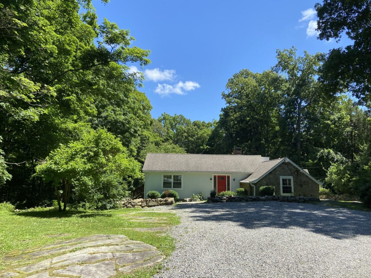 White house with red door, wooded setting.