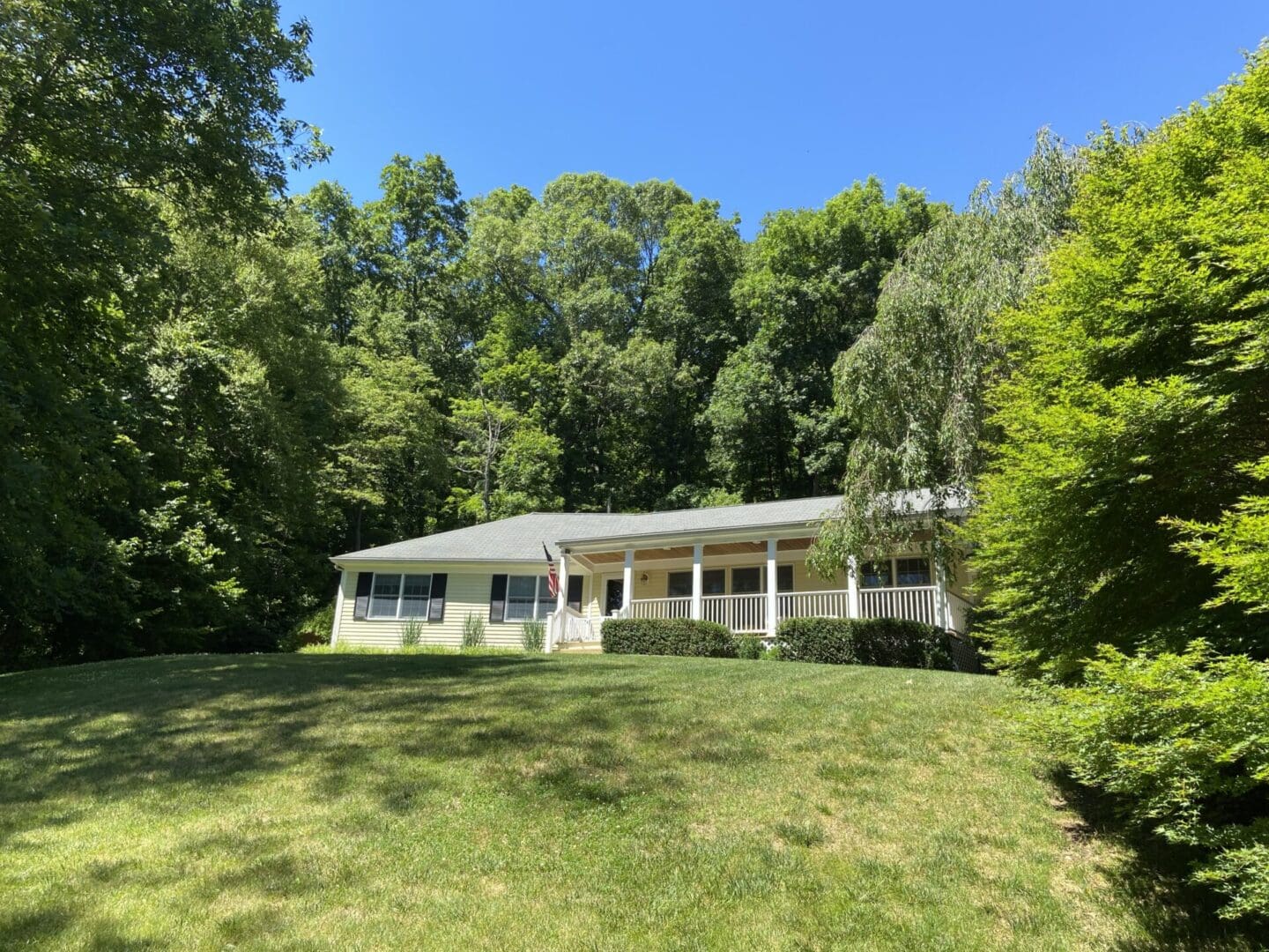 Yellow house with porch in the woods.