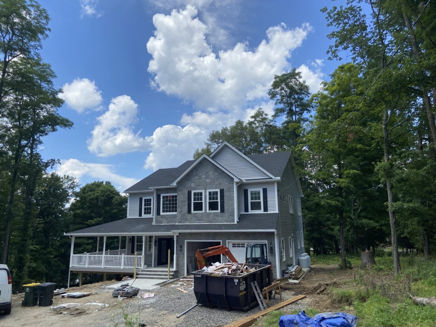 Two-story house under construction in woods.