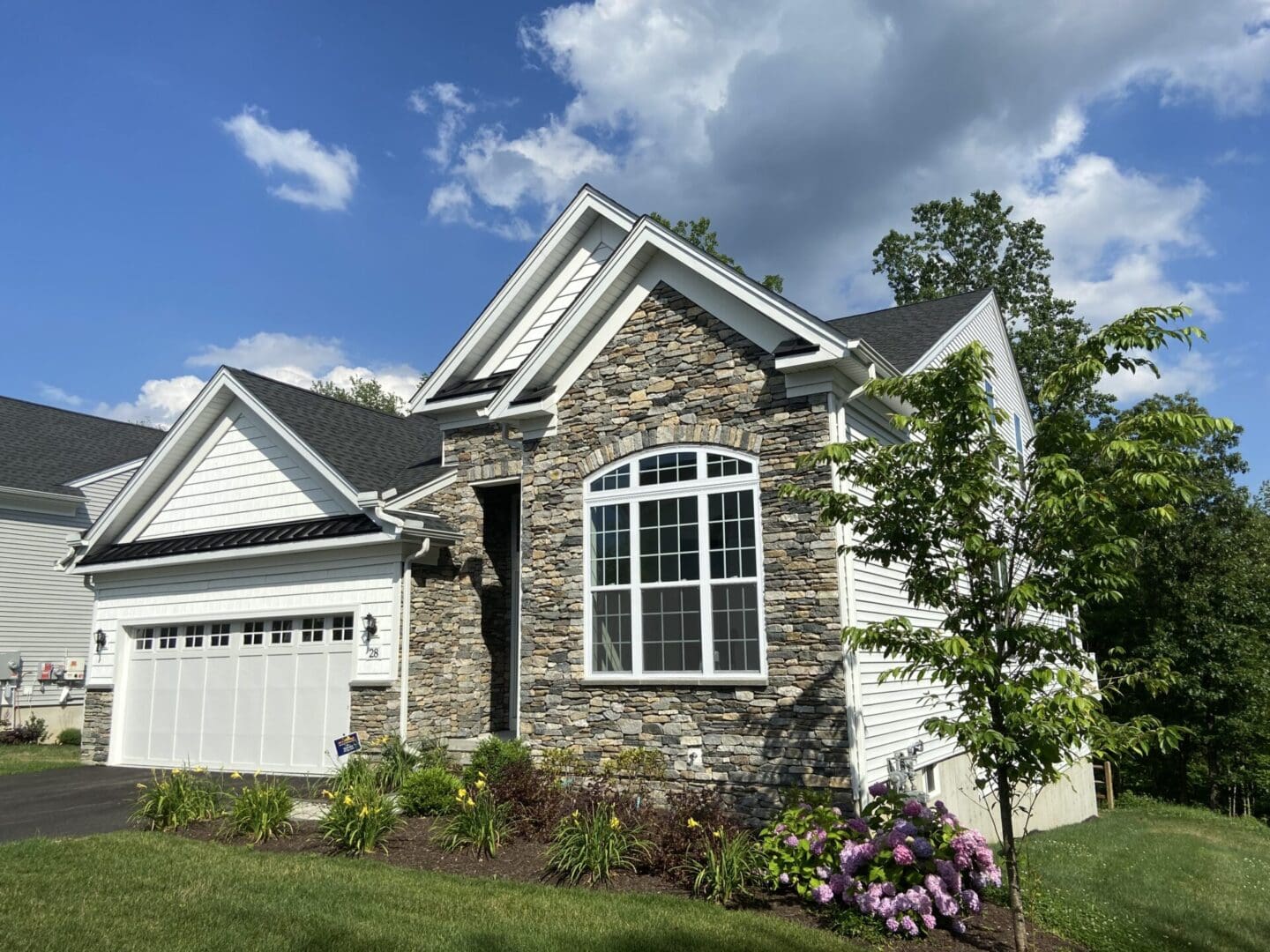 White house with stone facade and garage.