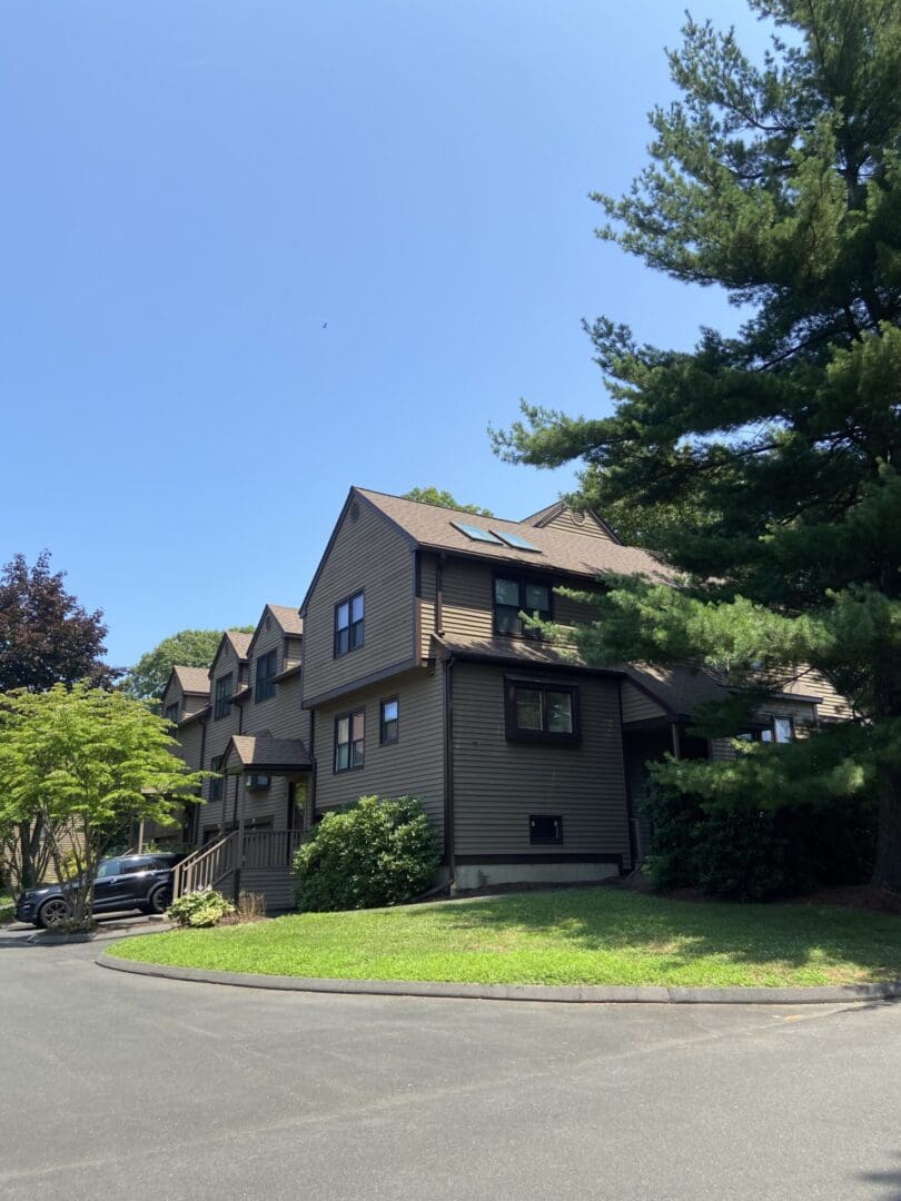 Tan townhouse with green lawn and trees.