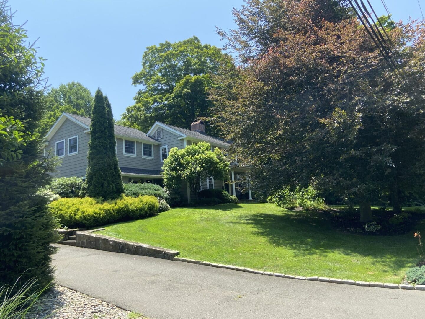 Gray house with green lawn and trees.