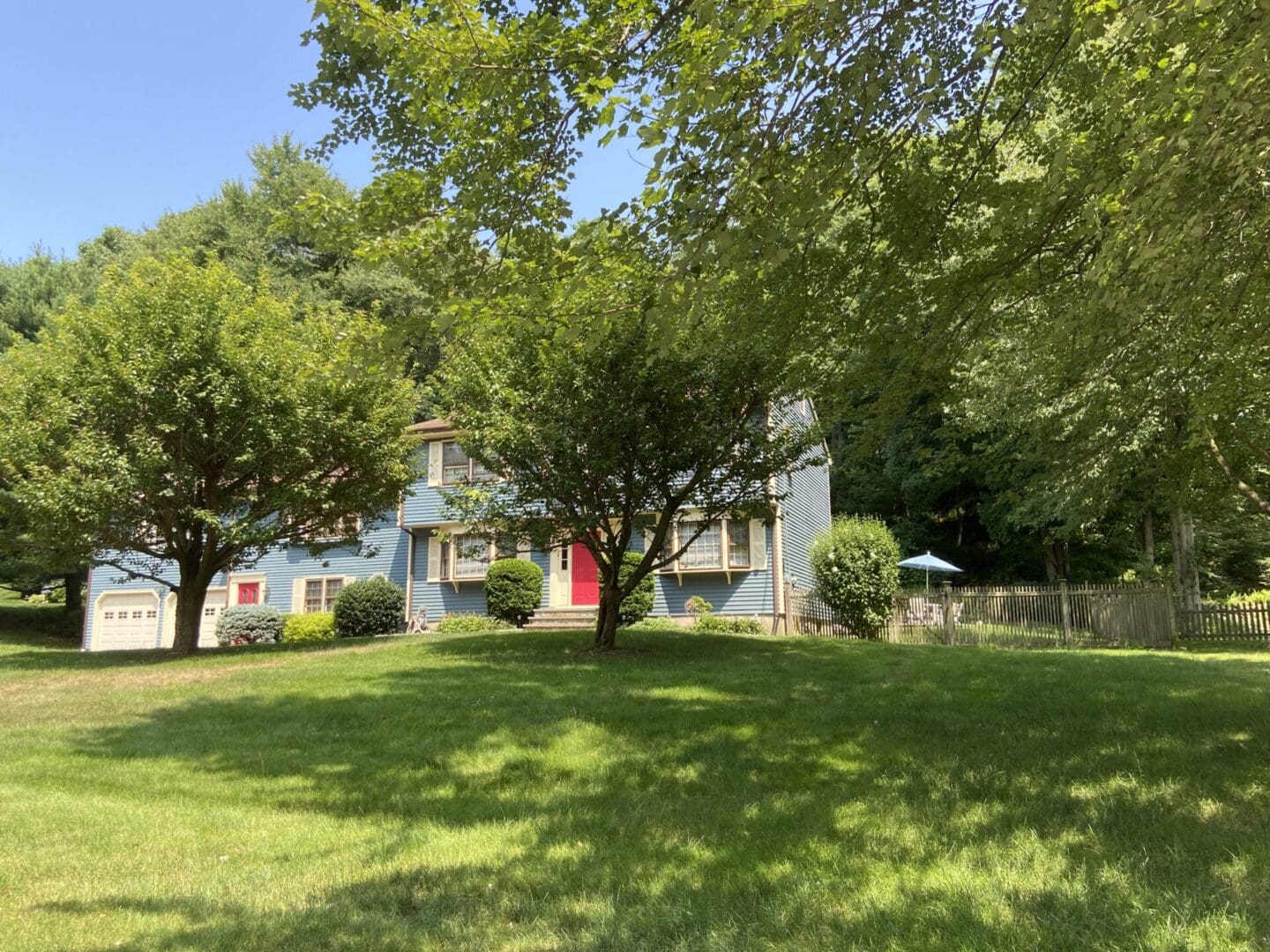 Blue house with red door on a lawn.